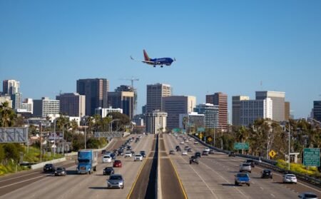 Airplane approaching San Diego airport over busy city freeway and skyline.